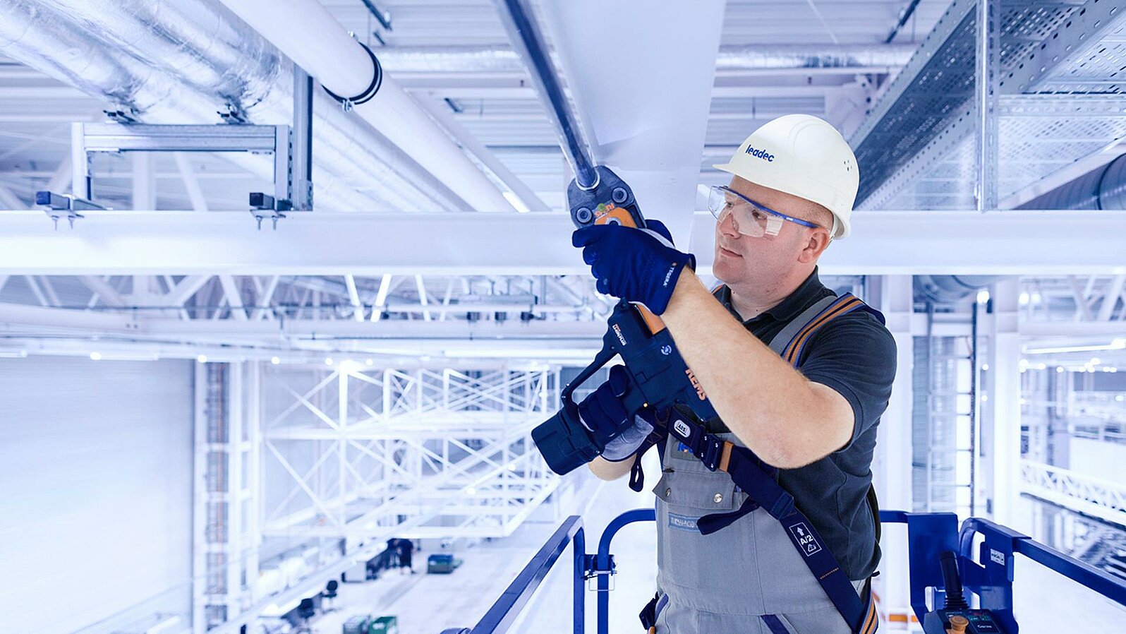 Leadec-Mitarbeiter bei der Installation der Medienversorgung an der Decke einer Fabrik.